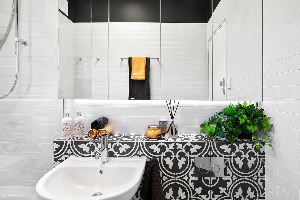 Cette image montre une petite salle de bain principale minimaliste avec un placard à porte vitrée, des portes de placard blanches, une baignoire posée, un combiné douche/baignoire, WC suspendus, un carrelage blanc, des carreaux de céramique, un mur noir, un sol en carrelage de céramique, un lavabo de ferme, un plan de toilette en carrelage, un sol noir et un plan de toilette noir.