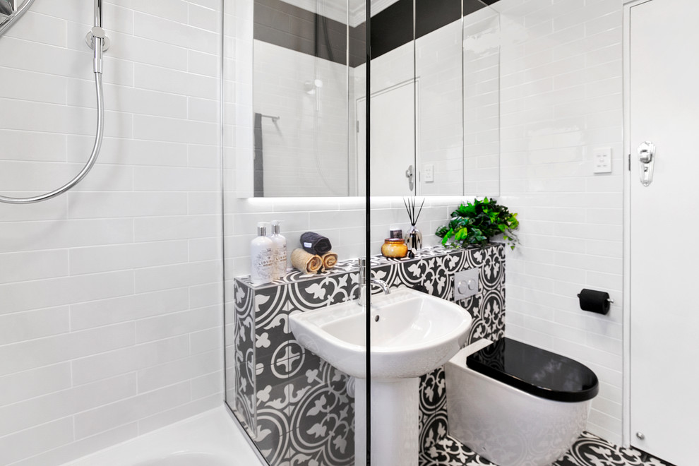 Idéer för ett litet modernt svart en-suite badrum, med luckor med glaspanel, vita skåp, ett platsbyggt badkar, en dusch/badkar-kombination, en vägghängd toalettstol, vit kakel, keramikplattor, svarta väggar, klinkergolv i keramik, ett piedestal handfat, kaklad bänkskiva, svart golv och med dusch som är öppen