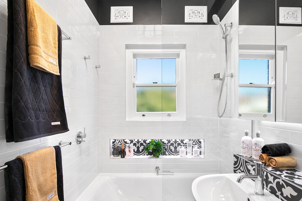 Exemple d'une petite salle de bain principale moderne avec un placard à porte vitrée, des portes de placard blanches, une baignoire posée, un combiné douche/baignoire, WC suspendus, un carrelage blanc, des carreaux de céramique, un mur noir, un sol en carrelage de céramique, un lavabo de ferme, un plan de toilette en carrelage, un sol noir et un plan de toilette noir.