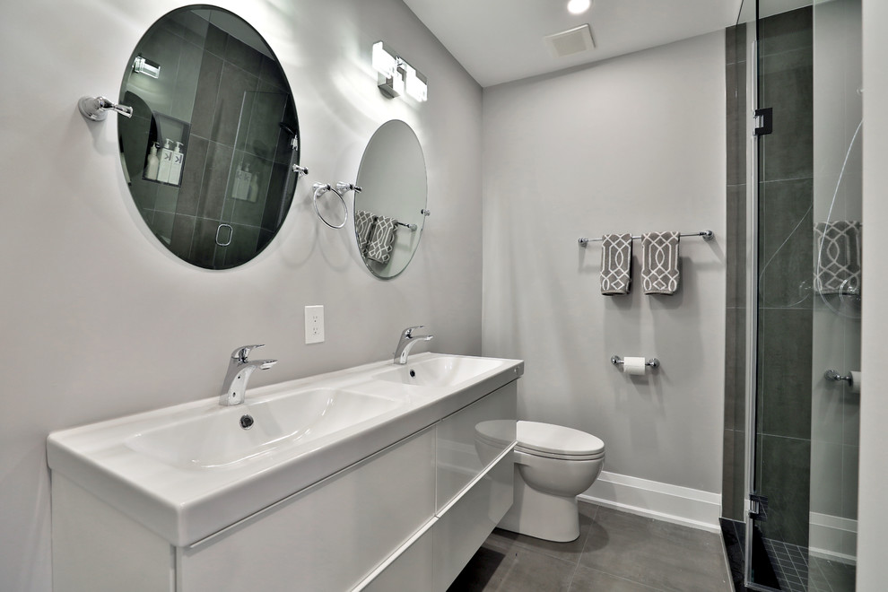 На фото: главная ванная комната среднего размера в стиле модернизм с белыми фасадами, ванной в нише, душем над ванной, унитазом-моноблоком, разноцветной плиткой, серыми стенами, раковиной с несколькими смесителями и душем с раздвижными дверями с