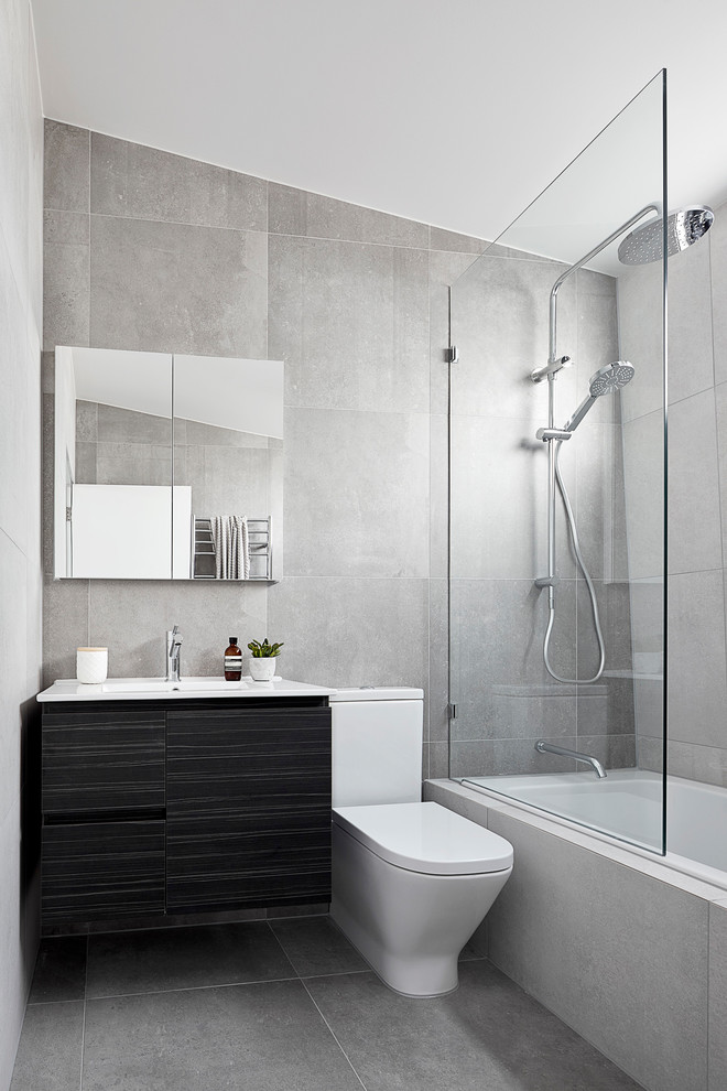 Пример оригинального дизайна: маленькая серо-белая ванная комната в стиле модернизм с фасадами островного типа, коричневыми фасадами, накладной ванной, душем над ванной, унитазом-моноблоком, серой плиткой, керамической плиткой, белыми стенами, полом из цементной плитки, душевой кабиной, подвесной раковиной, столешницей из искусственного камня, серым полом, душем с распашными дверями, белой столешницей, тумбой под одну раковину, подвесной тумбой и кессонным потолком для на участке и в саду