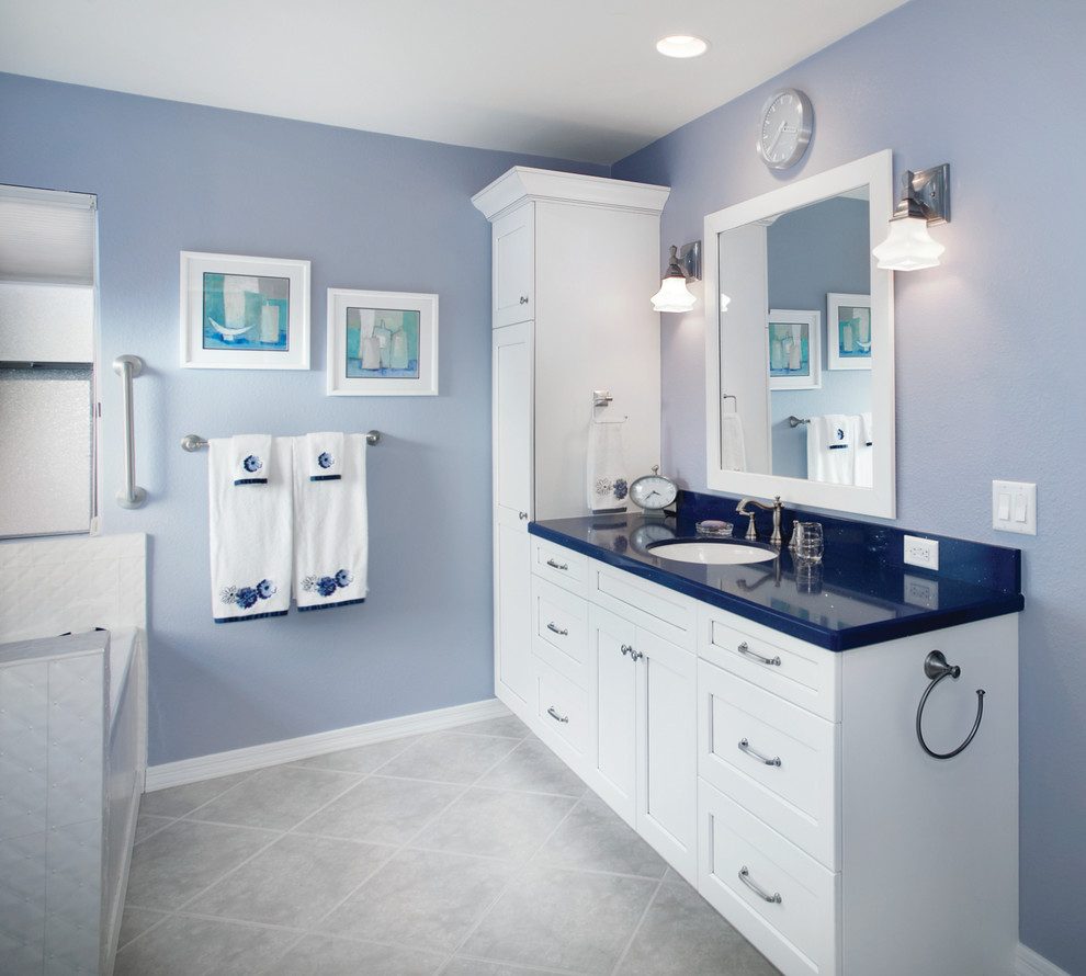 Cette photo montre une salle de bain chic avec un mur bleu, un lavabo encastré, un placard à porte shaker, des portes de placard blanches, une baignoire posée, un carrelage gris, des carreaux de porcelaine et un sol en carrelage de porcelaine.