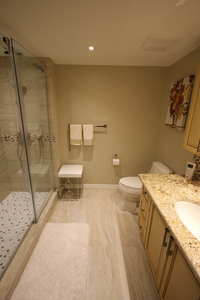 Aménagement d'une salle de bain principale classique de taille moyenne avec un placard avec porte à panneau surélevé, des portes de placard jaunes, une douche d'angle, WC à poser, un carrelage multicolore, un carrelage en pâte de verre, un mur beige, un sol en carrelage de céramique, un lavabo encastré, un plan de toilette en granite, un sol beige, une cabine de douche à porte coulissante et un plan de toilette beige.