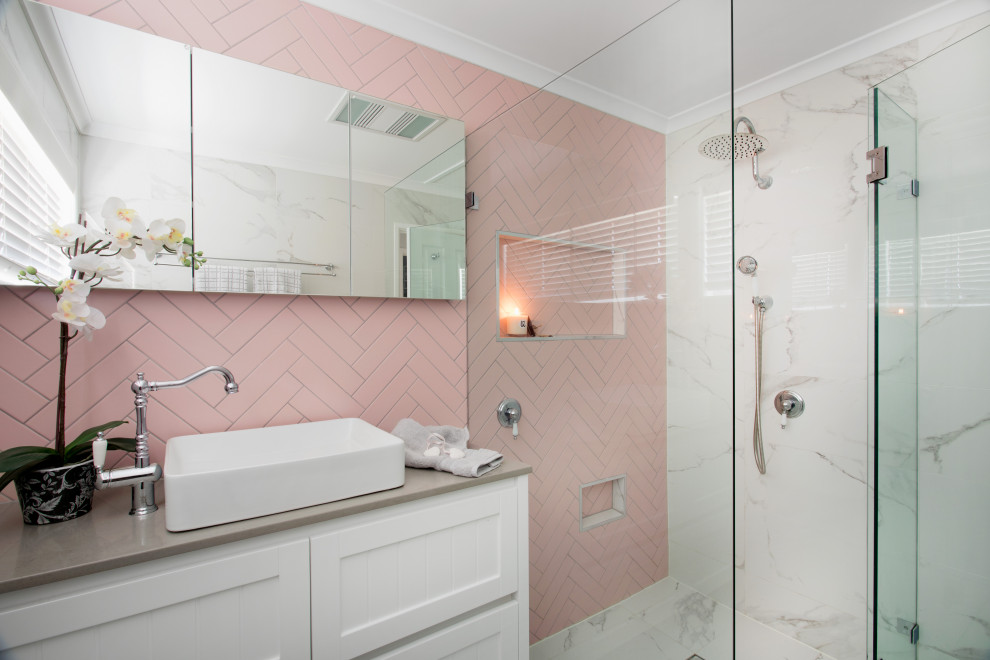 Inspiration pour une salle de bain traditionnelle de taille moyenne avec des portes de placard blanches, une douche d'angle, un carrelage rose, un lavabo posé, un sol gris, une cabine de douche à porte battante et un plan de toilette beige.