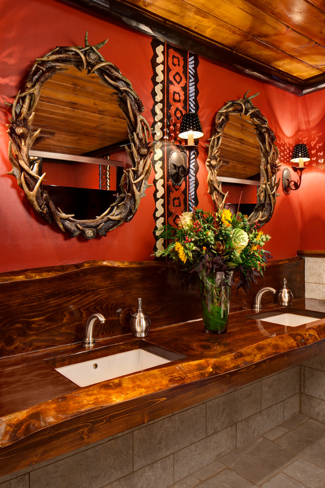 Example of a mountain style beige tile bathroom design in Milwaukee with an undermount sink, wood countertops and red walls