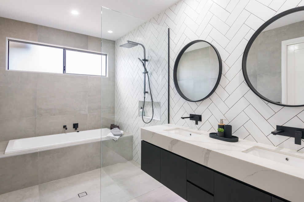 Modernes Badezimmer mit flächenbündigen Schrankfronten, schwarzen Schränken, Einbaubadewanne, Nasszelle, weißen Fliesen, Unterbauwaschbecken, grauem Boden, offener Dusche und weißer Waschtischplatte in Brisbane