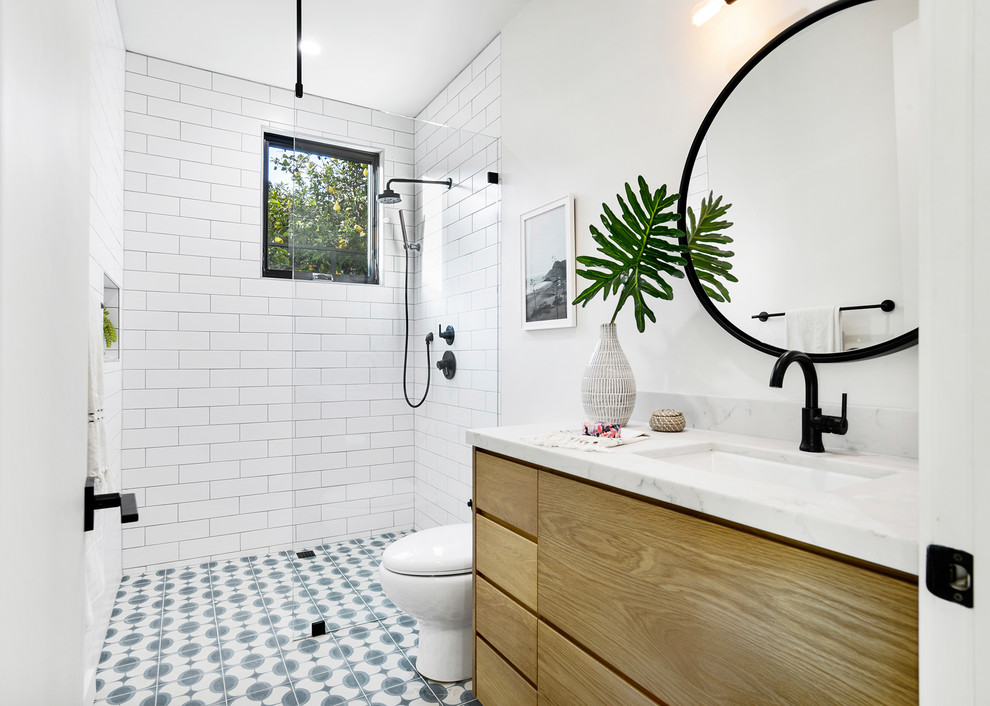 Bild på ett funkis vit vitt badrum med dusch, med släta luckor, en öppen dusch, vit kakel, tunnelbanekakel, vita väggar, klinkergolv i porslin, ett undermonterad handfat, bänkskiva i kvartsit, blått golv, skåp i mellenmörkt trä och med dusch som är öppen