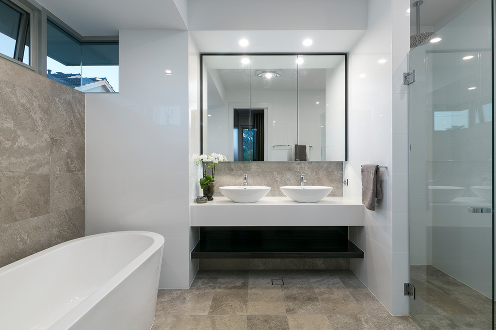 Источник вдохновения для домашнего уюта: большая ванная комната в стиле модернизм с белой плиткой, плиткой из травертина, серыми стенами, полом из травертина, серым полом, плоскими фасадами, темными деревянными фасадами, отдельно стоящей ванной, угловым душем, унитазом-моноблоком, душевой кабиной, настольной раковиной, столешницей из кварцита, душем с распашными дверями и белой столешницей