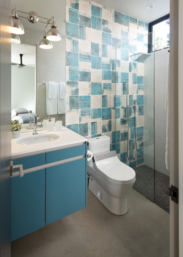 Exemple d'une salle de bain tendance de taille moyenne avec un placard à porte plane, des portes de placard bleues, WC à poser, un carrelage bleu, un carrelage blanc, des carreaux de céramique, un mur multicolore, sol en béton ciré, un lavabo encastré, un plan de toilette en surface solide, un sol gris et aucune cabine.