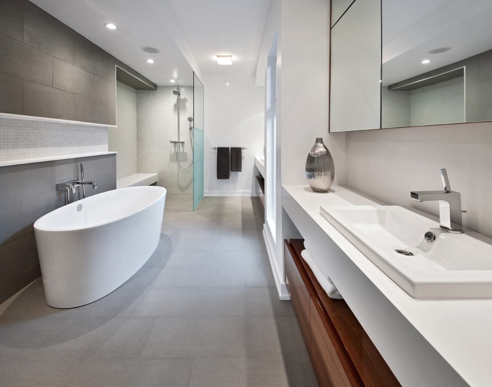 Photo of a contemporary bathroom in Ottawa with a built-in sink, flat-panel cabinets, medium wood cabinets, a freestanding bath, a walk-in shower, grey tiles and an open shower.
