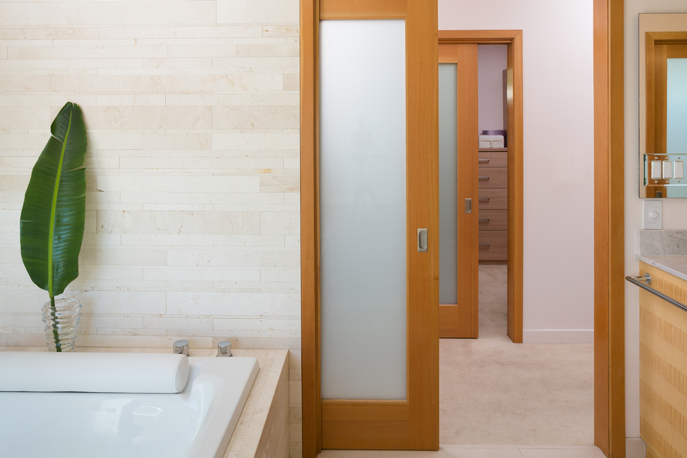 Exemple d'une grande salle de bain principale tendance en bois clair avec une grande vasque, un placard à porte plane, un plan de toilette en quartz, une baignoire posée, une douche ouverte, WC à poser, un carrelage beige, des dalles de pierre, un mur blanc et un sol en carrelage de céramique.
