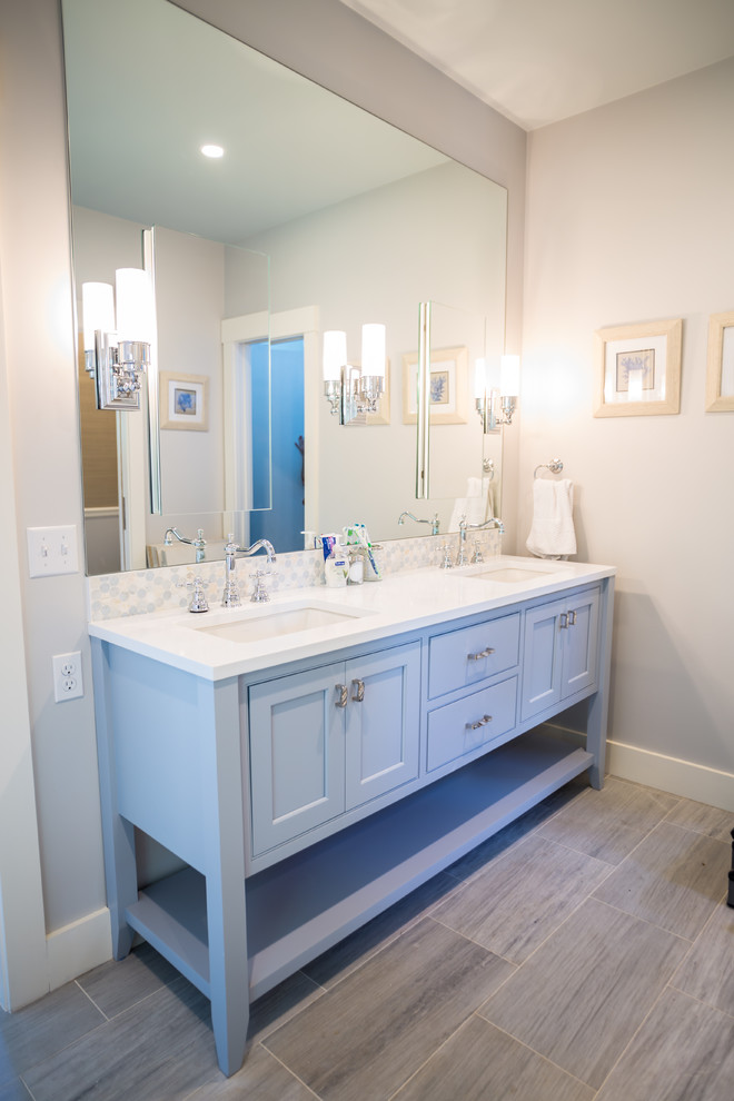 На фото: большая главная ванная комната в морском стиле с фасадами с филенкой типа жалюзи, синими фасадами, серой плиткой, керамогранитной плиткой, серыми стенами, полом из керамогранита и накладной раковиной с