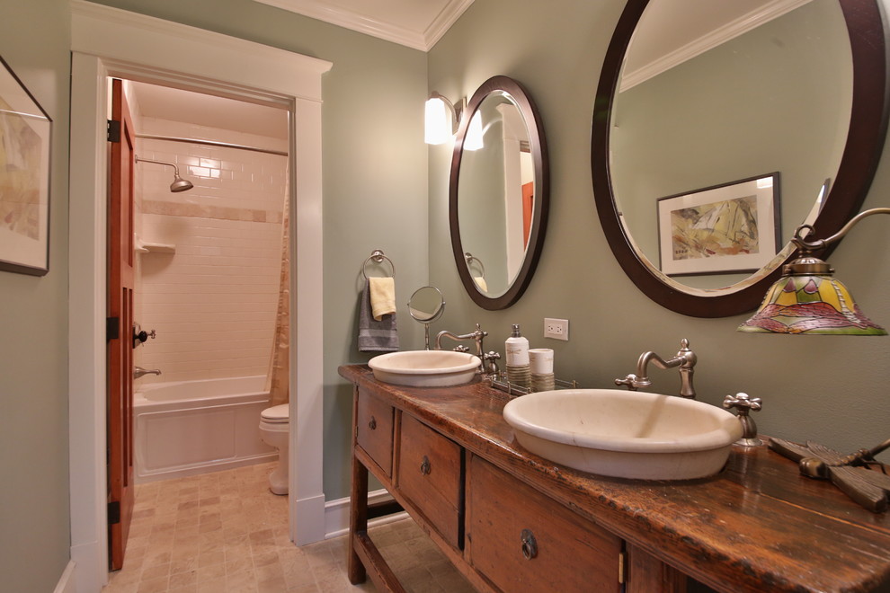 Inspiration pour une salle d'eau craftsman en bois brun de taille moyenne avec une baignoire en alcôve, un combiné douche/baignoire, WC à poser, un mur vert, un placard en trompe-l'oeil, un carrelage blanc, un carrelage métro, un sol en travertin, une vasque et un plan de toilette en bois.
