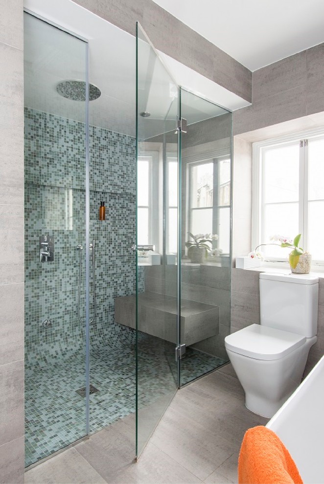 Exempel på ett mellanstort modernt badrum, med ett fristående badkar, en dubbeldusch, grå väggar, en toalettstol med separat cisternkåpa, mosaik, blå kakel, ett väggmonterat handfat, grått golv och dusch med gångjärnsdörr