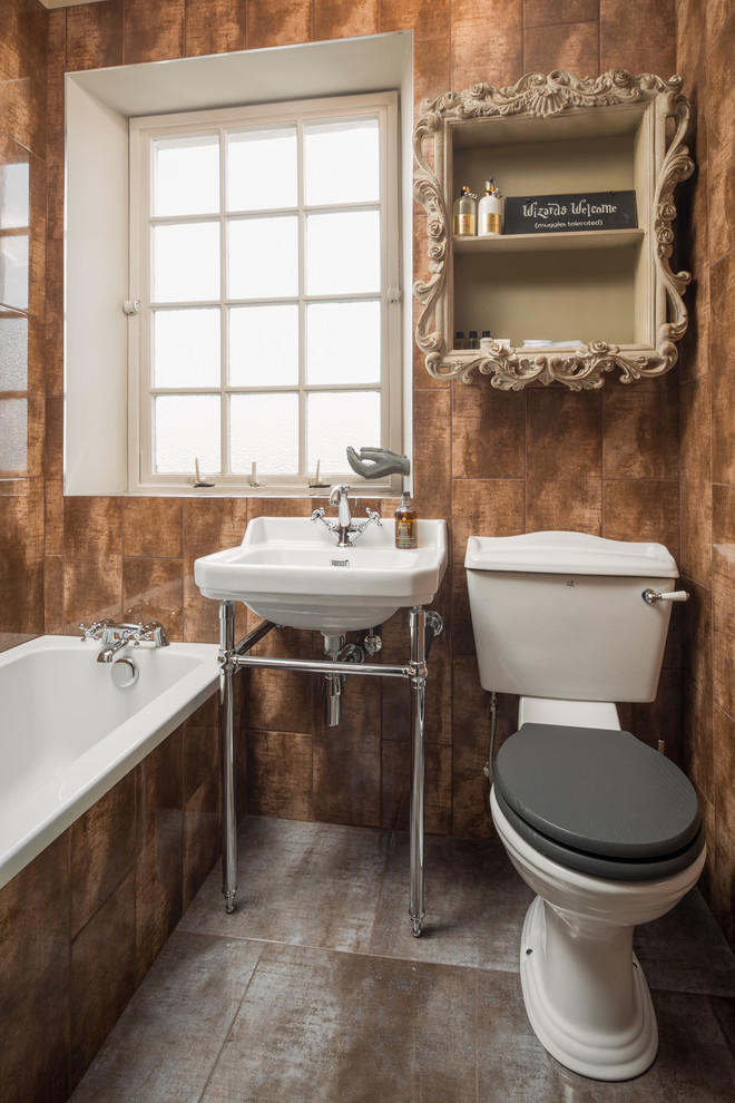 This is an example of a bohemian family bathroom in London with a built-in bath, a two-piece toilet, brown tiles and a console sink.