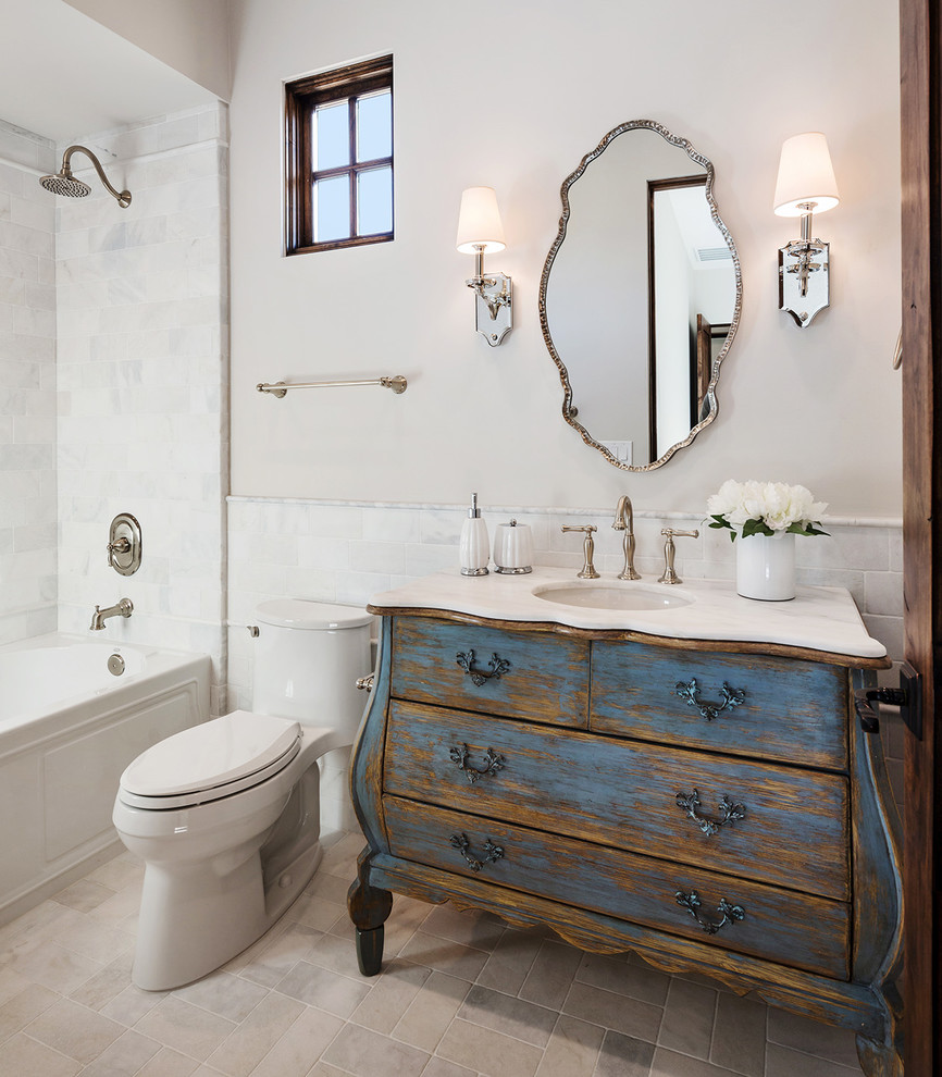 Idée de décoration pour une douche en alcôve méditerranéenne en bois vieilli de taille moyenne avec un placard en trompe-l'oeil, une baignoire en alcôve, un carrelage beige, un mur beige, un lavabo posé, un plan de toilette en marbre, un sol beige, une cabine de douche avec un rideau et un plan de toilette noir.