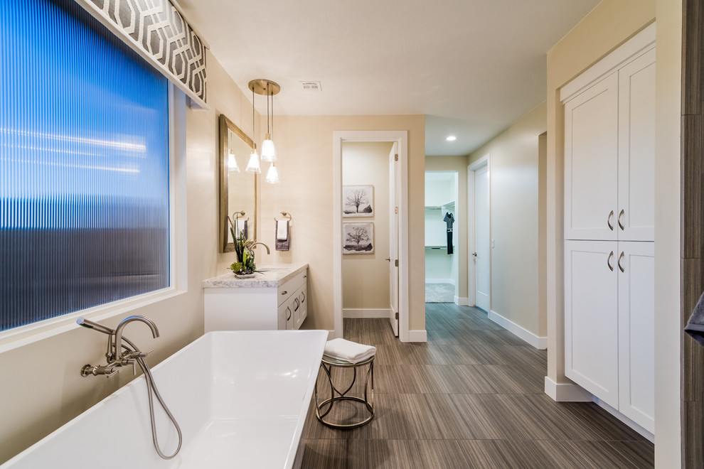 Immagine di una stanza da bagno padronale design di medie dimensioni con ante in stile shaker, ante bianche, vasca freestanding, pareti beige, pavimento in vinile, lavabo sottopiano e top in granito