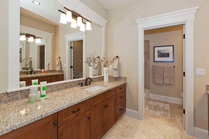 Esempio di un'ampia stanza da bagno padronale american style con lavabo integrato, ante in legno scuro, vasca da incasso, vasca/doccia e pareti beige