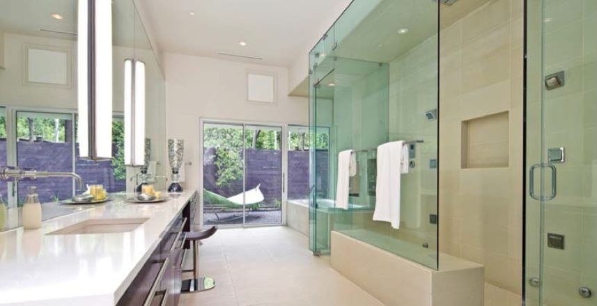 ダラスにある広いモダンスタイルのおしゃれなマスターバスルーム (フラットパネル扉のキャビネット、濃色木目調キャビネット、ドロップイン型浴槽、ダブルシャワー、白い壁、一体型シンク、珪岩の洗面台) の写真
