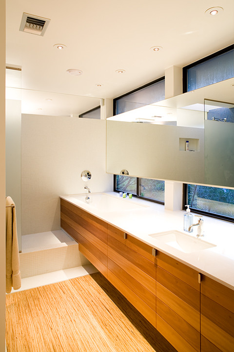 Cette photo montre une salle de bain principale moderne en bois brun de taille moyenne avec un placard à porte plane, des carreaux de céramique, un mur blanc, un plan de toilette en quartz, une baignoire encastrée, une douche d'angle, un carrelage blanc, un sol en contreplaqué et un lavabo encastré.
