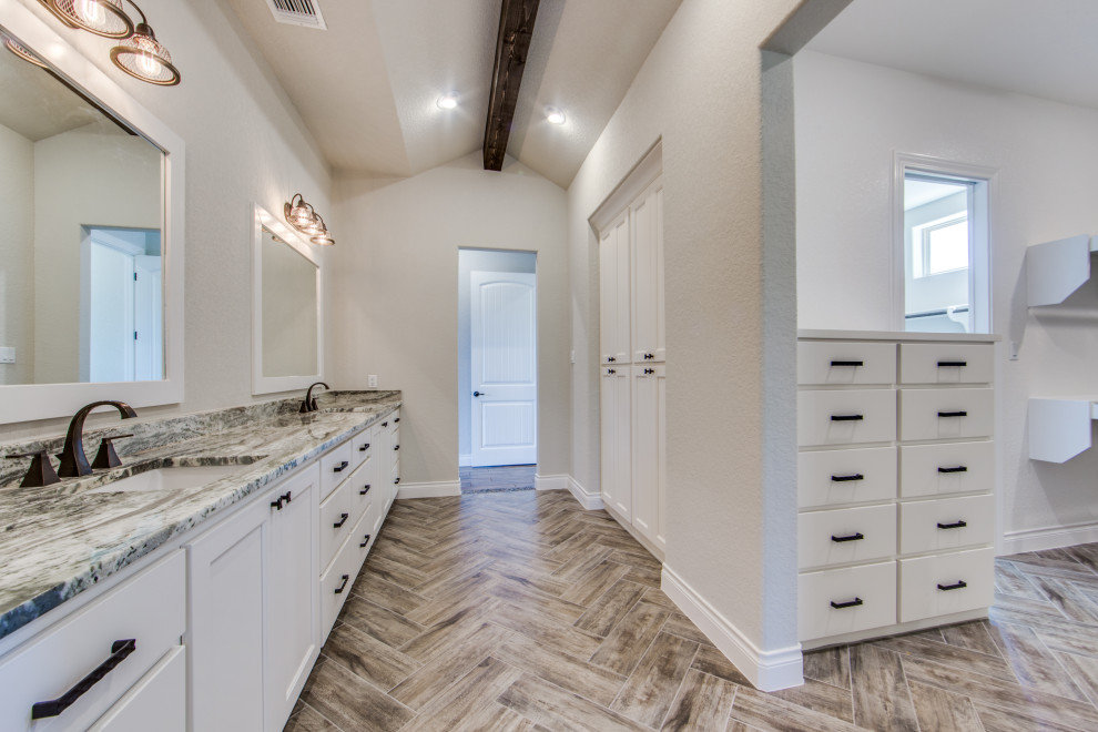 Large farmhouse ensuite bathroom in Austin with recessed-panel cabinets, white cabinets, a freestanding bath, a walk-in shower, a two-piece toilet, brown tiles, porcelain tiles, grey walls, porcelain flooring, a submerged sink, granite worktops, brown floors, an open shower and multi-coloured worktops.