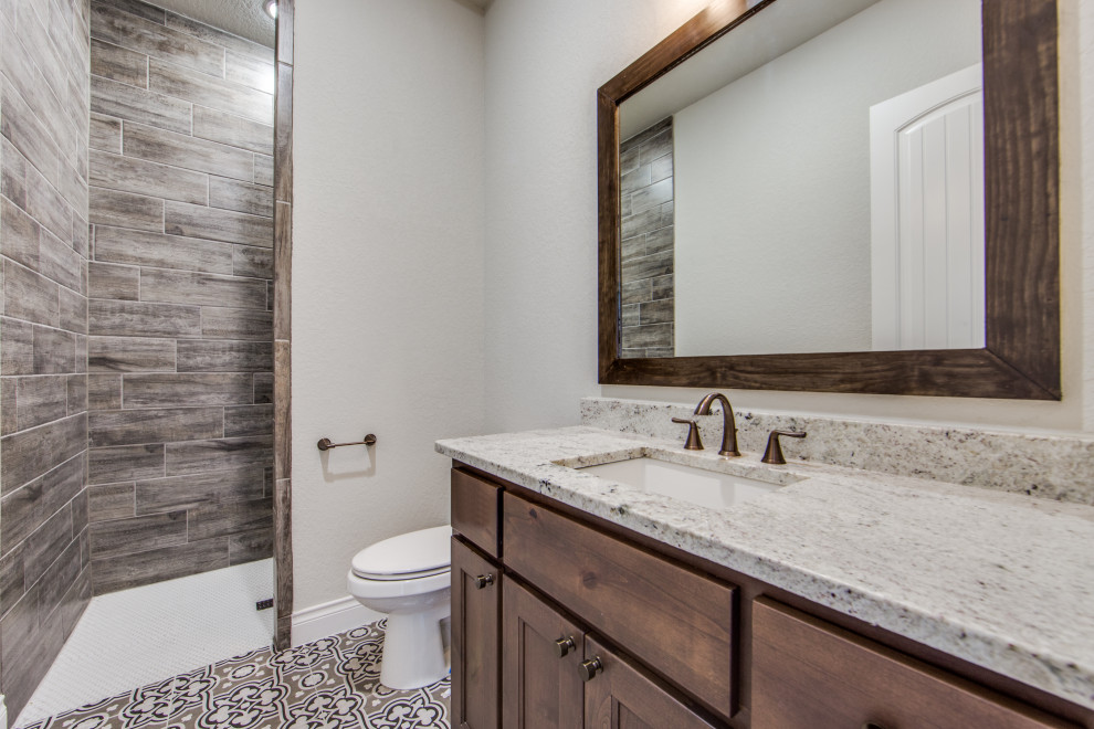 Inspiration for a large country master brown tile and porcelain tile ceramic tile and multicolored floor bathroom remodel in Austin with recessed-panel cabinets, dark wood cabinets, a two-piece toilet, gray walls, an undermount sink, granite countertops and gray countertops