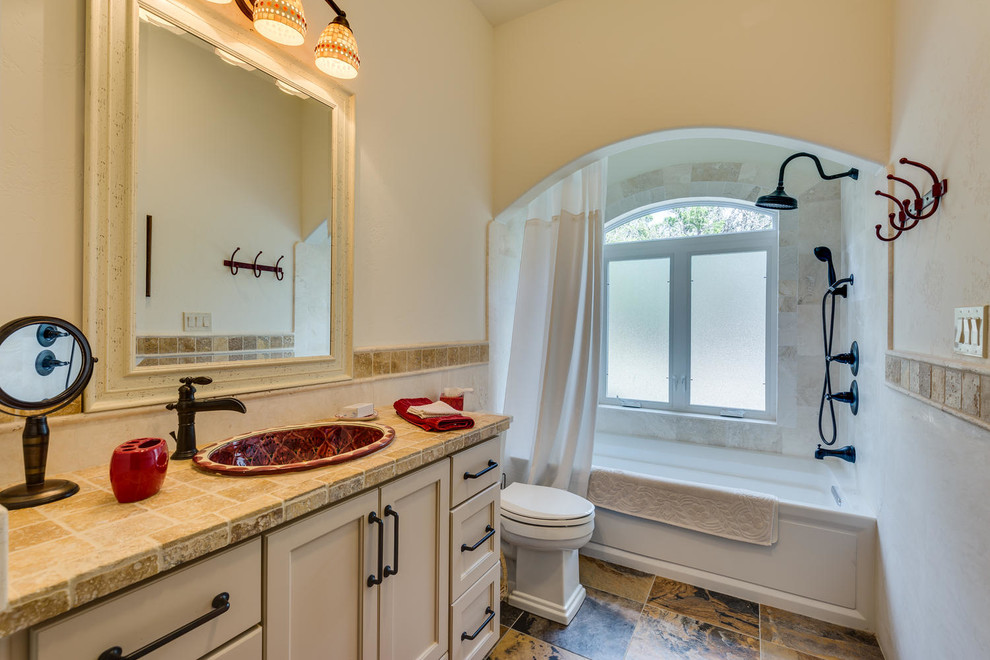 На фото: ванная комната среднего размера в классическом стиле с фасадами с утопленной филенкой, бежевыми фасадами, ванной в нише, душем над ванной, раздельным унитазом, бежевой плиткой, плиткой из травертина, бежевыми стенами, полом из сланца, душевой кабиной, накладной раковиной, столешницей терраццо, разноцветным полом и шторкой для ванной с