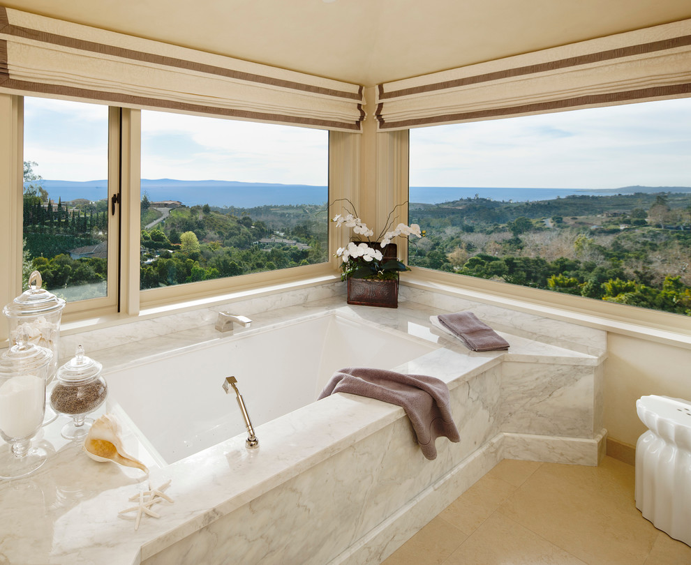 Idee per una stanza da bagno padronale tradizionale con top in marmo, vasca sottopiano, piastrelle beige, piastrelle in pietra, pareti beige e pavimento in laminato