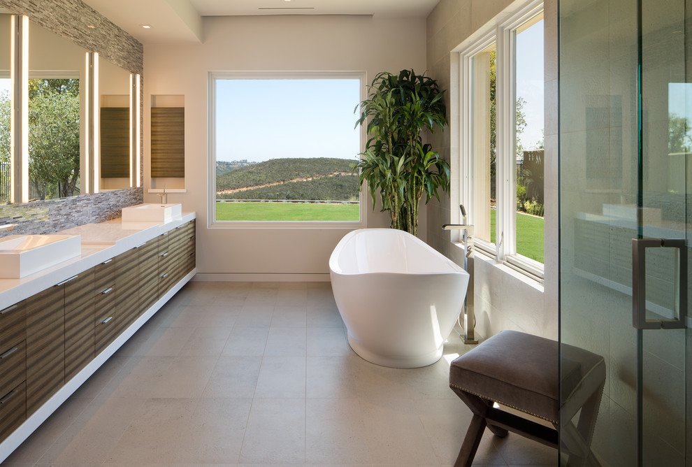 サンディエゴにあるコンテンポラリースタイルのおしゃれなマスターバスルーム (フラットパネル扉のキャビネット、茶色いキャビネット、置き型浴槽、グレーの壁、グレーの床) の写真