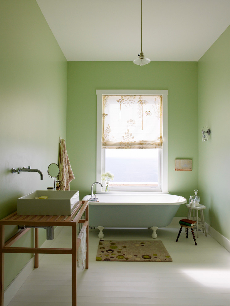 Inredning av ett maritimt en-suite badrum, med skåp i ljust trä, ett badkar med tassar, gröna väggar, målat trägolv, ett fristående handfat, träbänkskiva och vitt golv