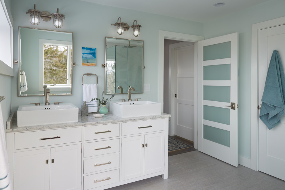 Aménagement d'une salle de bain bord de mer avec un placard à porte shaker, des portes de placard blanches, un mur bleu, une vasque, un sol gris et un plan de toilette gris.