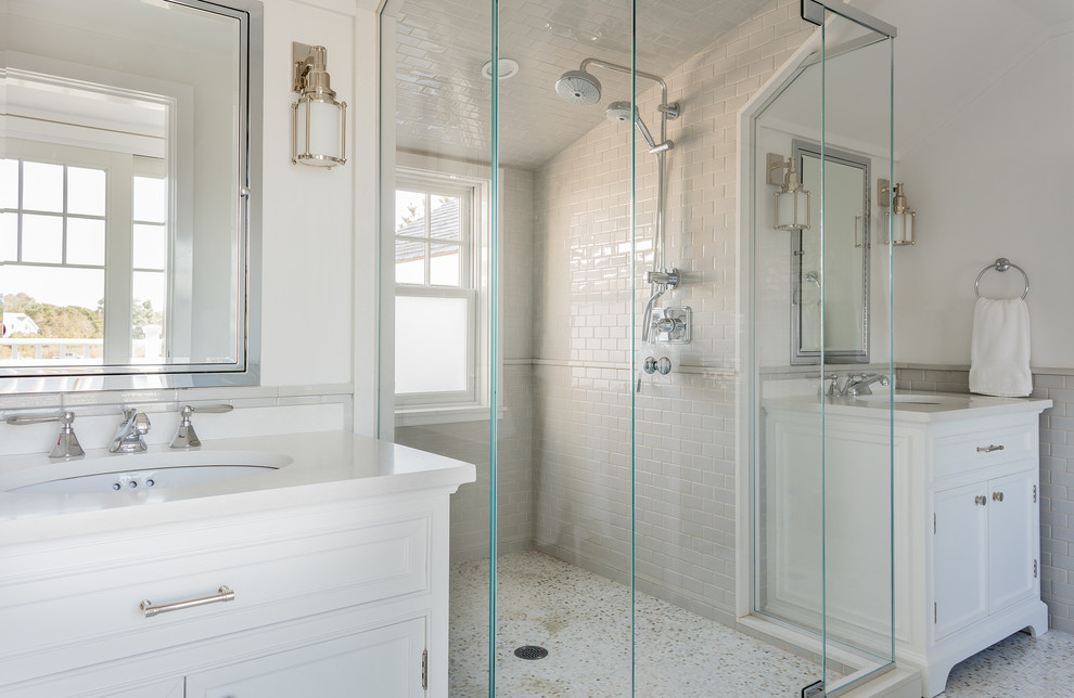 Photo of a large beach style ensuite bathroom in Boston with shaker cabinets, white cabinets, an alcove shower, white tiles, metro tiles, white walls, mosaic tile flooring, a submerged sink and solid surface worktops.