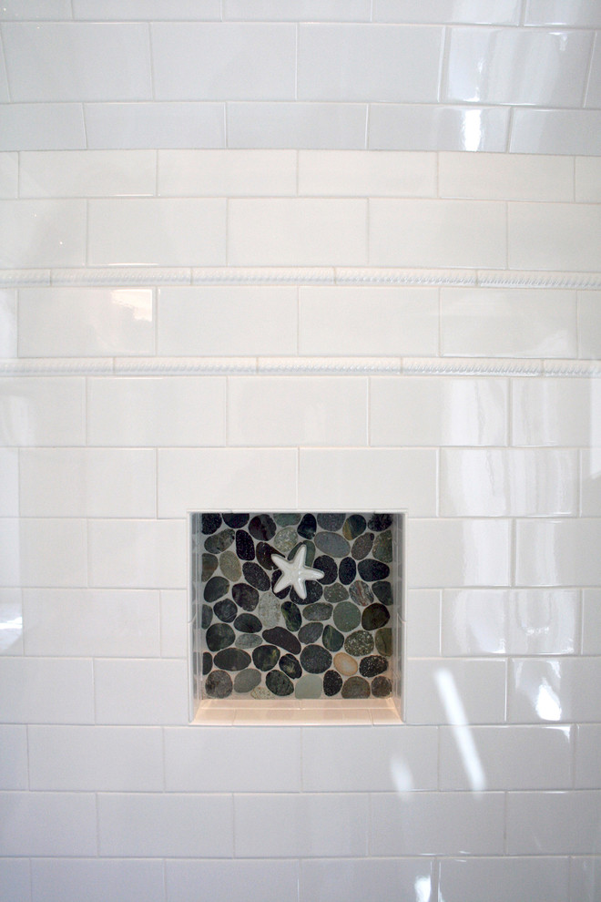Nautical bathroom in Boston with white tiles, pebble tiles, white walls and pebble tile flooring.