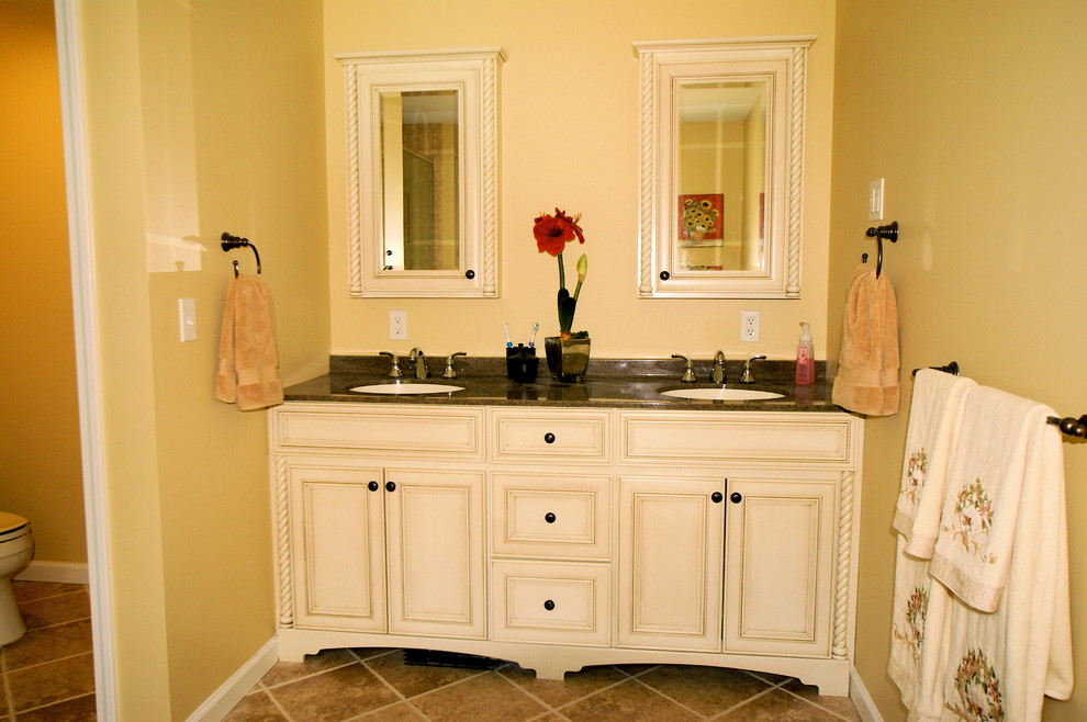 Mittelgroßes Klassisches Badezimmer En Suite mit Schrankfronten mit vertiefter Füllung, weißen Schränken, Toilette mit Aufsatzspülkasten, gelber Wandfarbe, Keramikboden, Unterbauwaschbecken und Mineralwerkstoff-Waschtisch in Newark