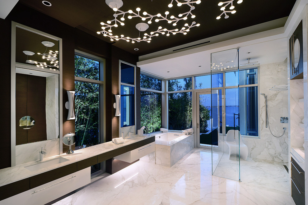 На фото: главная ванная комната в современном стиле с плоскими фасадами, белыми фасадами, полновстраиваемой ванной, душем без бортиков, белой плиткой, мраморной плиткой, коричневыми стенами, мраморным полом, врезной раковиной, белым полом, душем с распашными дверями и зеркалом с подсветкой с