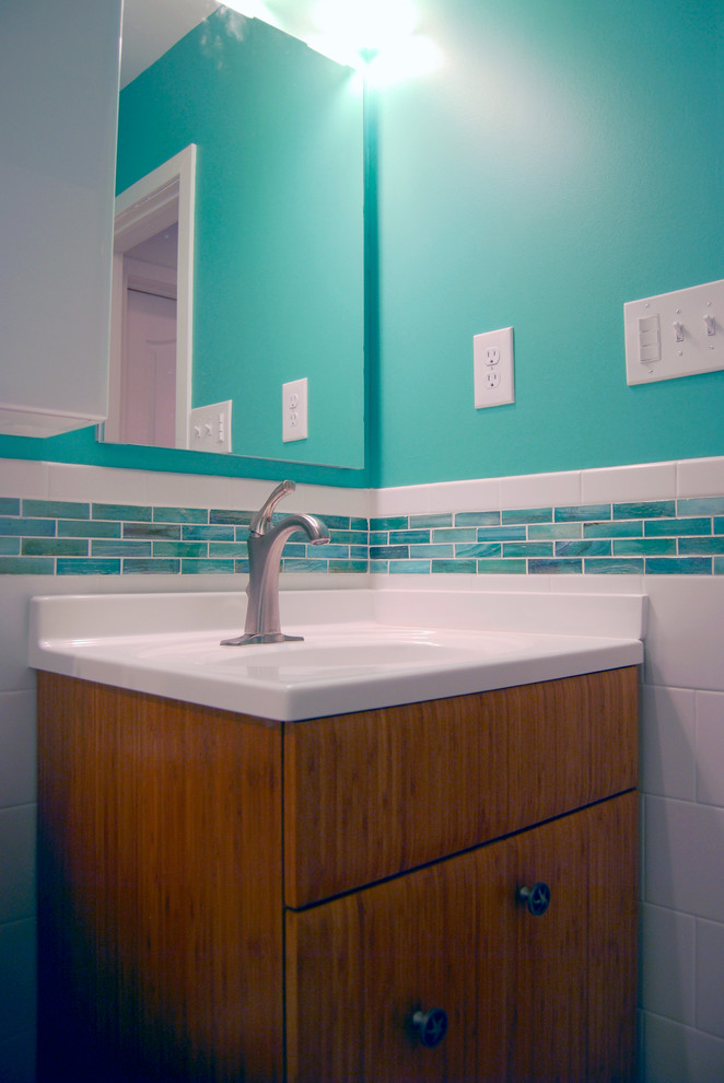 Foto på ett litet funkis badrum med dusch, med ett konsol handfat, släta luckor, skåp i mellenmörkt trä, bänkskiva i akrylsten, ett badkar i en alkov, en dusch/badkar-kombination, en toalettstol med separat cisternkåpa, blå väggar och klinkergolv i porslin