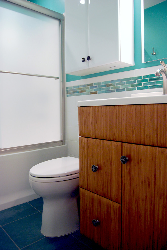 Aménagement d'une petite salle d'eau contemporaine en bois brun avec un plan vasque, un placard à porte plane, un plan de toilette en surface solide, une baignoire en alcôve, un combiné douche/baignoire, WC séparés, un mur bleu et un sol en carrelage de porcelaine.