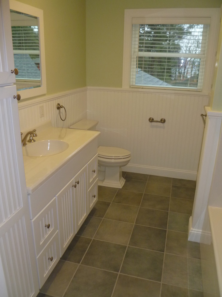 На фото: большая ванная комната в классическом стиле с белыми фасадами, ванной в нише, душем над ванной, серой плиткой, керамической плиткой, зелеными стенами, полом из керамической плитки, душевой кабиной, монолитной раковиной и столешницей из ламината