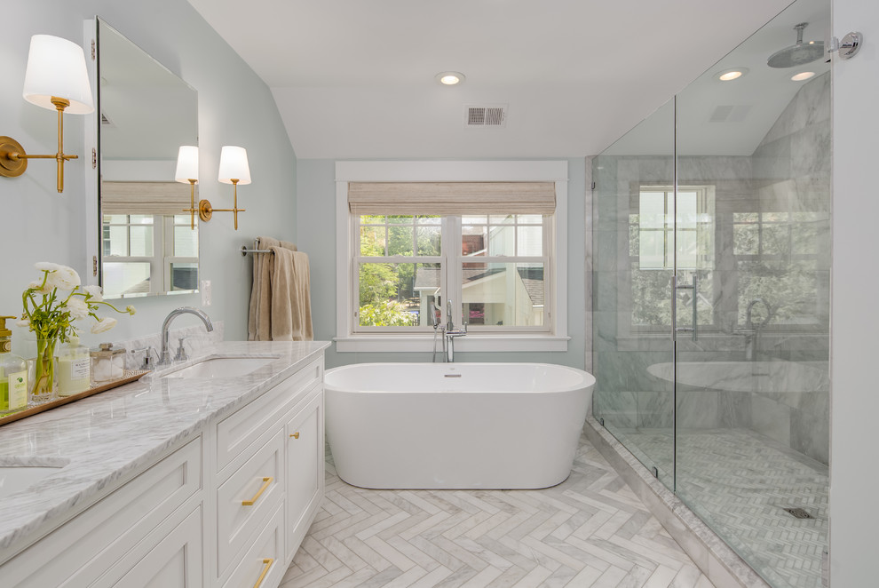 Klassisk inredning av ett vit vitt en-suite badrum, med luckor med profilerade fronter, vita skåp, ett fristående badkar, grå kakel, grå väggar, ett undermonterad handfat och vitt golv