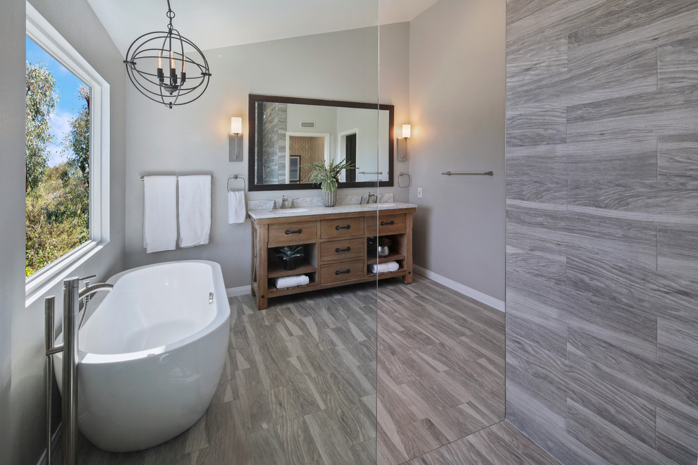 Bathroom - large contemporary master gray tile and porcelain tile medium tone wood floor and gray floor bathroom idea in Orange County with medium tone wood cabinets, gray walls, an undermount sink, furniture-like cabinets, a one-piece toilet and marble countertops