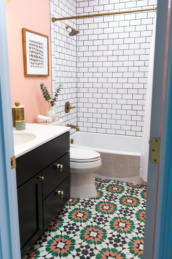 На фото: ванная комната среднего размера в современном стиле с разноцветным полом, фасадами с утопленной филенкой, черными фасадами, ванной в нише, душем над ванной, раздельным унитазом, белой плиткой, плиткой кабанчик, розовыми стенами, душевой кабиной, врезной раковиной, столешницей из искусственного камня, шторкой для ванной, белой столешницей и полом из керамической плитки с