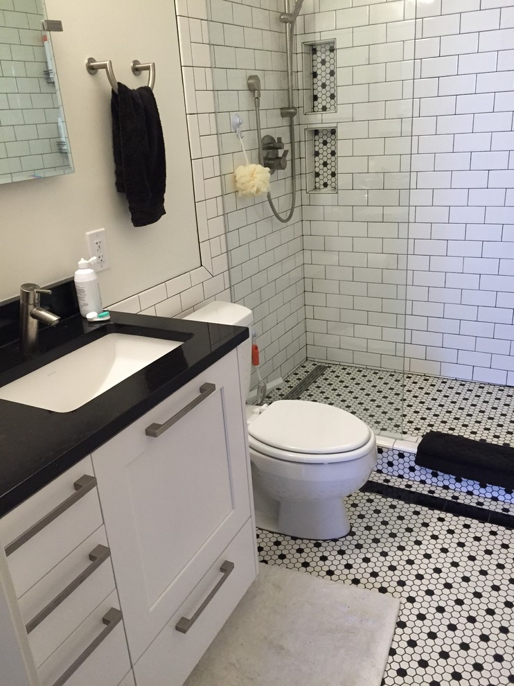 Photo of a small classic shower room bathroom in Salt Lake City with shaker cabinets, white cabinets, an alcove bath, a shower/bath combination, a one-piece toilet, white tiles, metro tiles, grey walls, ceramic flooring, a submerged sink, solid surface worktops, white floors, a hinged door and black worktops.