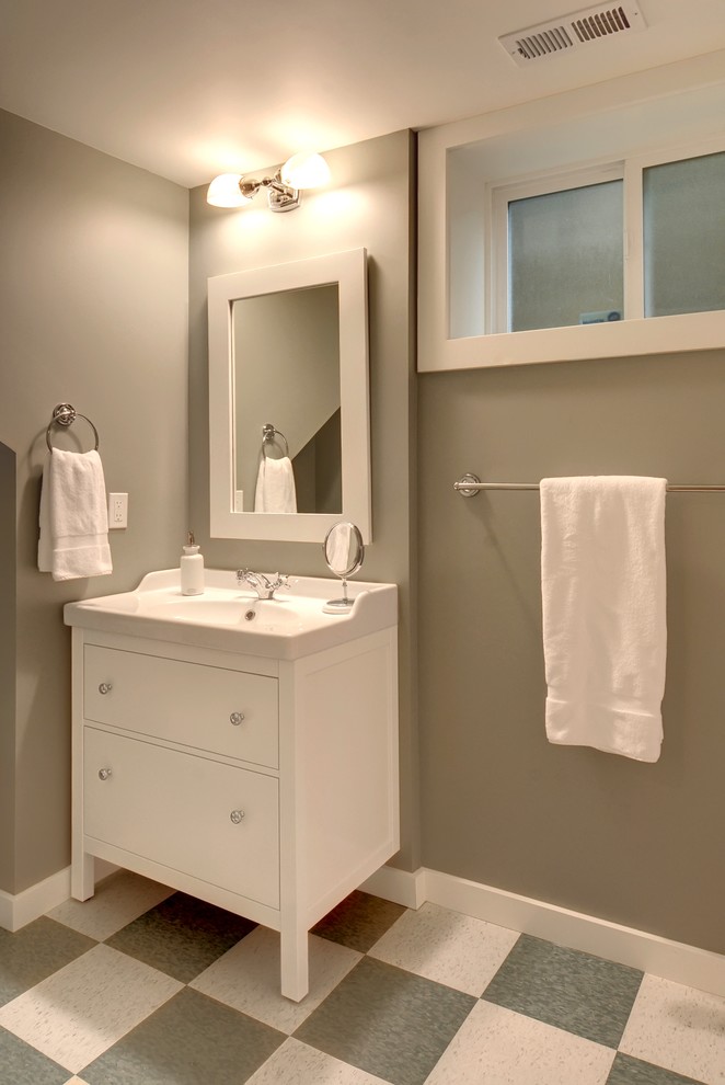 Cette image montre une salle d'eau craftsman avec des portes de placard blanches, un mur gris et un sol en linoléum.