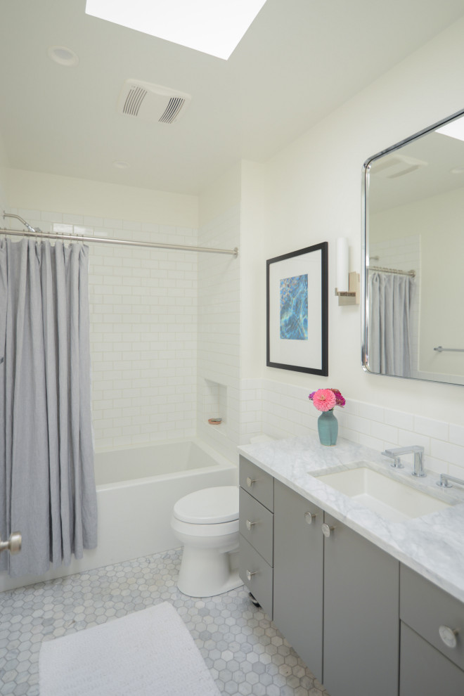 Exempel på ett mellanstort klassiskt grå grått badrum med dusch, med släta luckor, grå skåp, ett badkar i en alkov, en dusch/badkar-kombination, en toalettstol med separat cisternkåpa, vit kakel, tunnelbanekakel, vita väggar, marmorgolv, ett undermonterad handfat, marmorbänkskiva, grått golv och dusch med duschdraperi