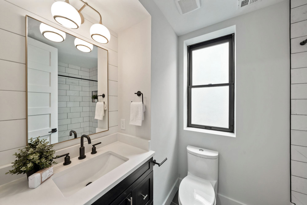 Photo of a small contemporary bathroom in DC Metro with shaker cabinets, black cabinets, an alcove shower, a one-piece toilet, white tiles, metro tiles, a submerged sink, solid surface worktops, a sliding door, white worktops, a wall niche, a single sink and a built in vanity unit.