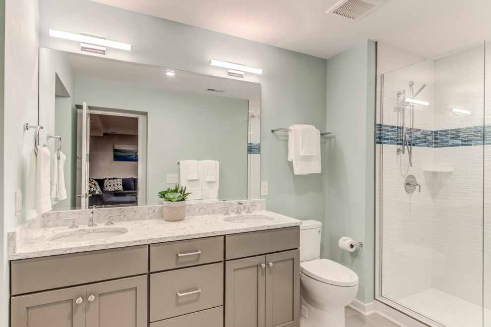 Idéer för att renovera ett mellanstort maritimt grå grått badrum med dusch, med luckor med upphöjd panel, bruna skåp, ett fristående badkar, keramikplattor, blå väggar, vinylgolv, ett undermonterad handfat, bänkskiva i kvartsit, grått golv och dusch med gångjärnsdörr