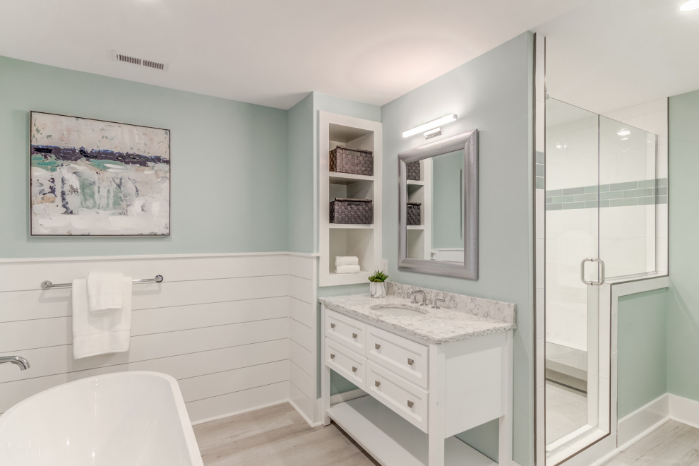 Example of a mid-sized beach style master ceramic tile vinyl floor, gray floor and single-sink bathroom design in Wilmington with raised-panel cabinets, gray cabinets, blue walls, an undermount sink, marble countertops, a hinged shower door, gray countertops and a freestanding vanity