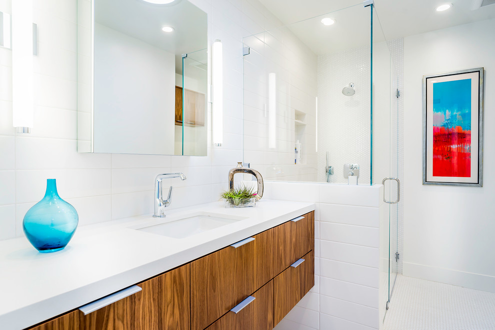 На фото: большая ванная комната в современном стиле с врезной раковиной, плоскими фасадами, фасадами цвета дерева среднего тона, угловым душем, белой плиткой, белыми стенами и полом из мозаичной плитки