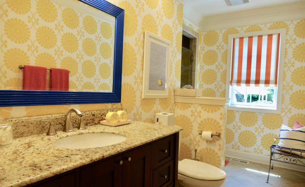 クリーブランドにあるトラディショナルスタイルのおしゃれな浴室 (家具調キャビネット、濃色木目調キャビネット、コーナー設置型シャワー、一体型トイレ	、ベージュのタイル、セラミックタイル、黄色い壁、セラミックタイルの床、アンダーカウンター洗面器、御影石の洗面台、ベージュの床、開き戸のシャワー、マルチカラーの洗面カウンター、洗面台1つ、独立型洗面台、壁紙) の写真