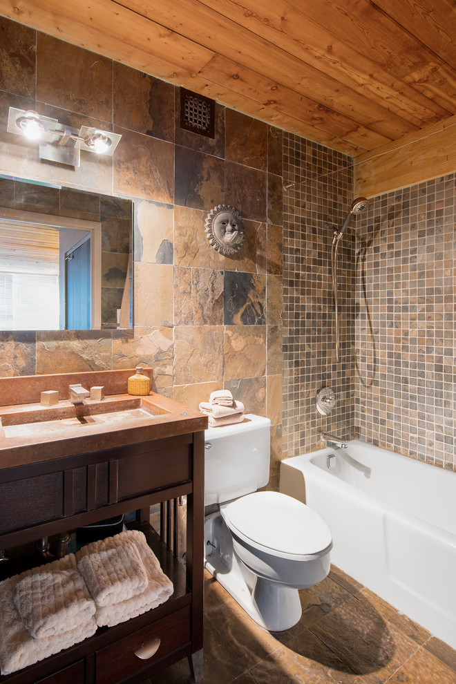 Bild på ett mellanstort rustikt badrum med dusch, med öppna hyllor, skåp i mörkt trä, ett badkar i en alkov, en dusch/badkar-kombination, en toalettstol med hel cisternkåpa, brun kakel, grå kakel, skifferkakel, beige väggar, skiffergolv, ett integrerad handfat, bänkskiva i onyx, brunt golv och dusch med duschdraperi